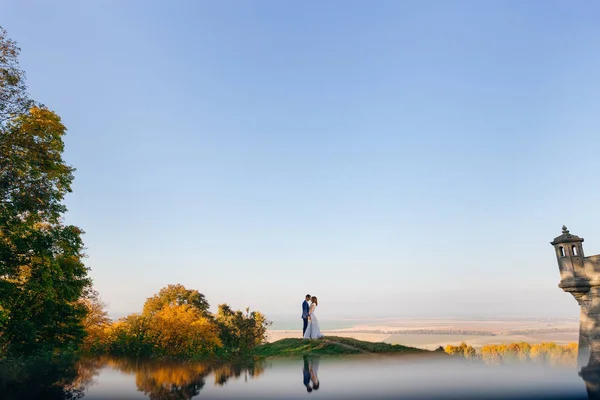 Jeunes mariés sur la prairie d'automne sur le fond de bleu sans nuages s — Photo