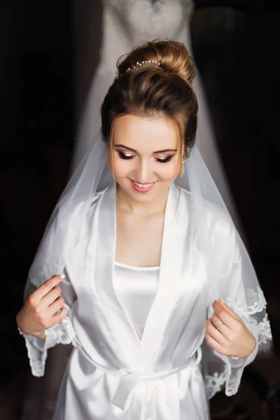Krásná nevěsta v bílém županu s make-upem a svatební závoj c — Stock fotografie