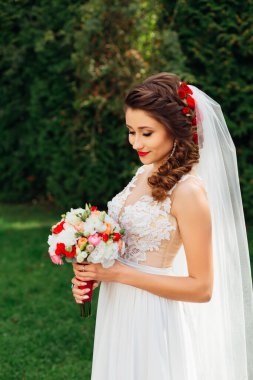 bride with bright makeup looks at wedding bouquet. Elegant weddi