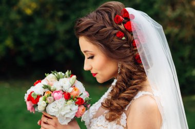 profile of bride with chic hairstyle holds wedding bouquet and c