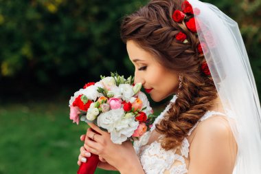 profile of bride with chic hairstyle holds wedding bouquet and c