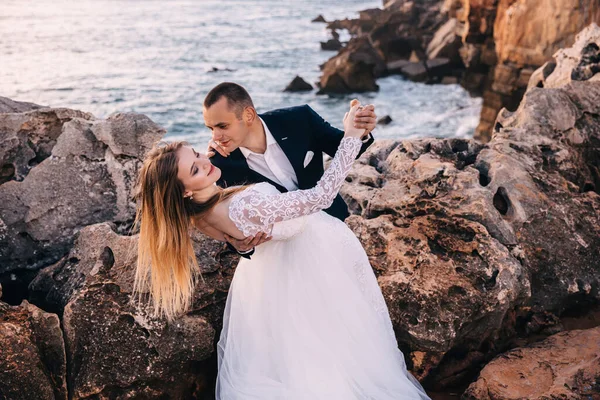 Newlyweds are dancing among the rocks overlooking the ocean. the — Stok fotoğraf