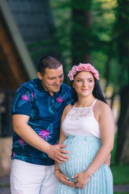 young expectant mother in a beautiful dress with a wreath on her