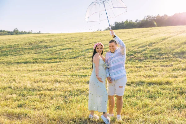 Couple dans des vêtements élégants sur le terrain avec parapluie transparent. Hum — Photo