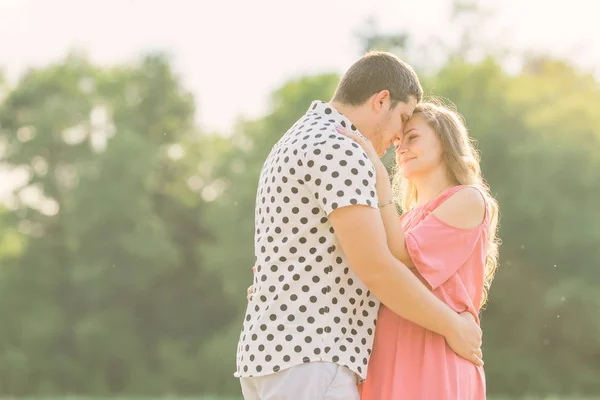 A férj gyengéden megöleli a terhes feleségét rózsaszín ruhában. egy pár. — Stock Fotó