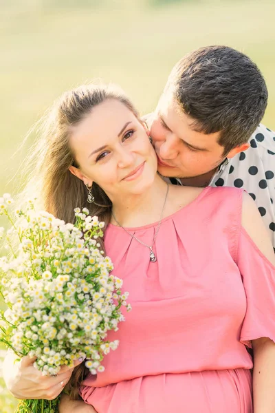 Zwangere vrouw houdt boeket bloemen vast en de man kust haar. clos — Stockfoto