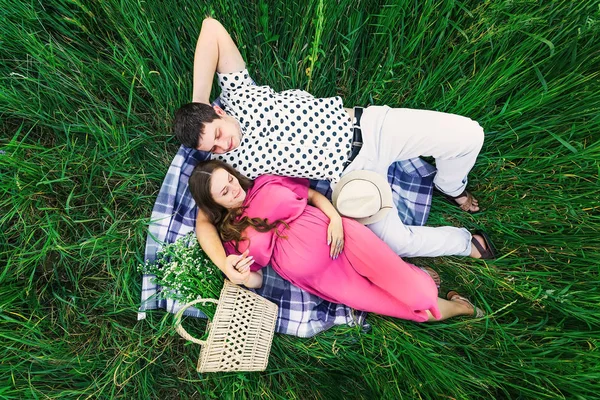 Genç aile manzarası. Kadın ve erkek battaniyenin üzerinde uzanırlar. — Stok fotoğraf