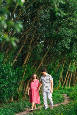 young family holding hands and walking in park. pregnant woman i