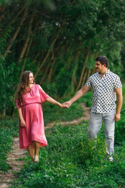 husband hugging pregnant wife in pink dress. expectant parents w