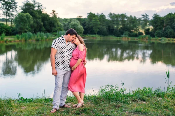 Teneri abbracci di genitori in attesa sullo sfondo del lago e per — Foto Stock