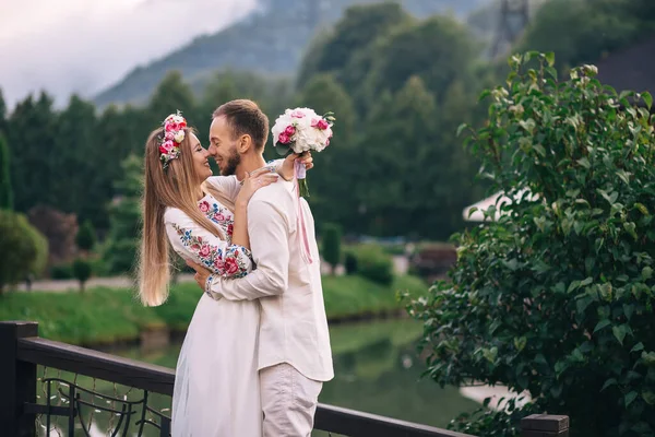 Brudgummen kramar och kysser bruden. nygifta på bakgrunden — Stockfoto