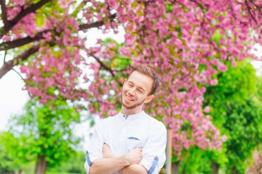 Sakallı adam gözlerini kapadı ve çiçek açan ağaçların yanındaki parkta gülümsedi.