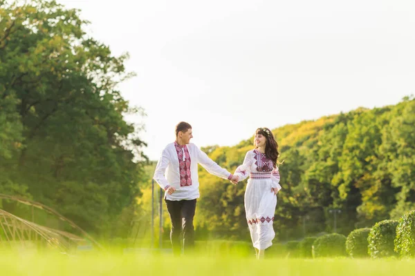 一个男人和一个穿绣花衣服的女孩牵着手跑 在公园里相爱的夫妻互相望着对方 — 图库照片