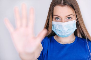 Covid-19 ve Hava kirliliği pm2.5 konsepti. Koronavirüsü korumak için maske takan ve Corona virüsünü durdurmak için el hareketi yapan genç bir kadın..