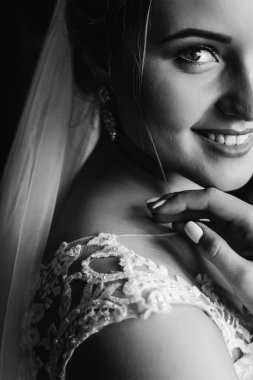 Gelinin yüzünün alt kısmını gülümseyerek yakın plan çekeceğiz. Bulanık arkaplan.