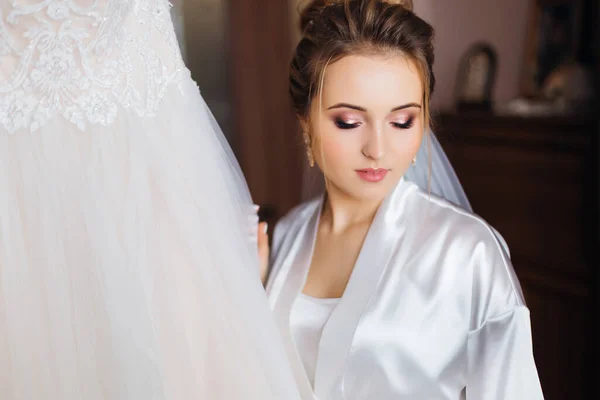 白いバスローブに美しいメイクの花嫁 レースと結婚式のドレスの近くの花嫁のクローズ — ストック写真