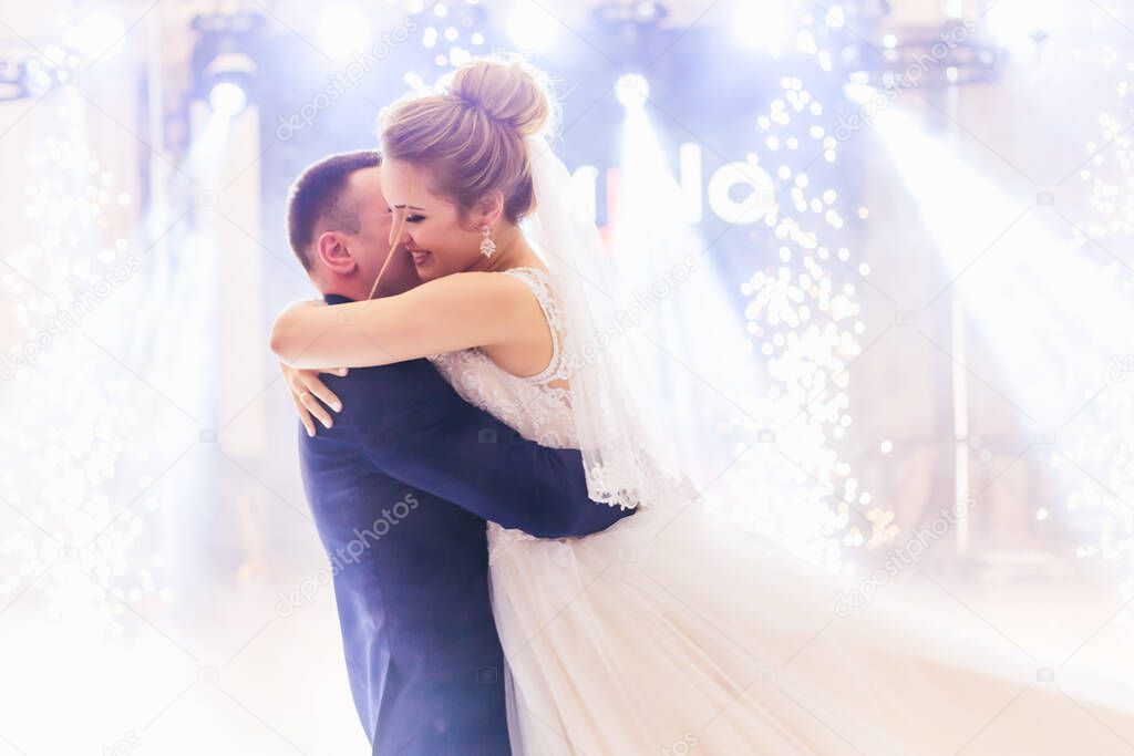 hall of restaurant with light, smoke and fireworks. sensual wedding dance with hugs.