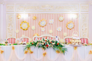 Düğün resepsiyonu Duvarda çiçekler ve baş harflerle süslenmiş yeni evliler için masa..