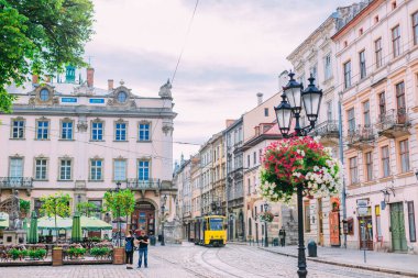 Lviv, Ukrayna - 17 Haziran 2018 - tramvay rayları ve güzel fenerleri olan eski kasaba meydanı. Sarı tramvay. Şehir meydanındaki kafe..