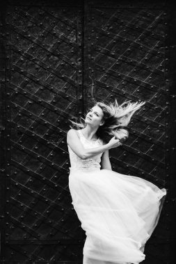 Güzel elbiseli gelin siyah kapının arkasında saçlarını sallıyor..