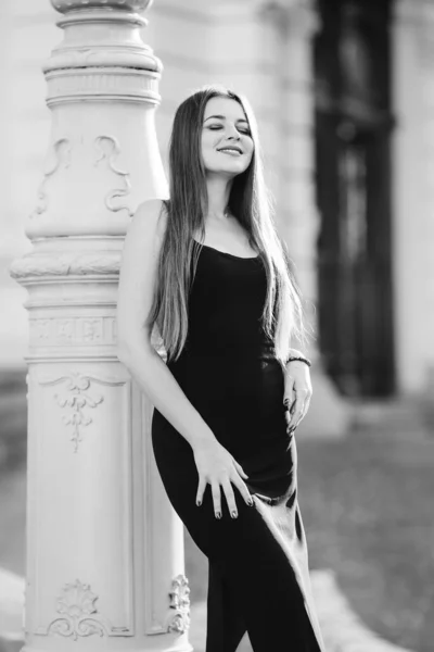 Dziewczyna Długimi Włosami Czarnej Sukience Stanowi Pobliżu Kolumny Czarno Białym — Zdjęcie stockowe