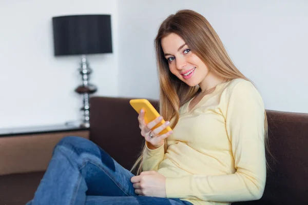 Jovem Mulher Sofá Segurando Smartphone Olhando Para Câmera — Fotografia de Stock