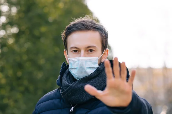 Man wearing mask show stop hands gesture for stop corona virus outbreak. Coronavirus concept.