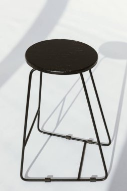 Beyaz arka planda gölgeli minimal siyah mat sandalyesi.