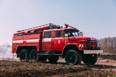 Yazın kırmızı itfaiye arabası kuraklık tarlasında sarı ve soluk çimlerle