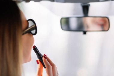 Kız arabadaki dikiz aynasına dudak boyuyor..