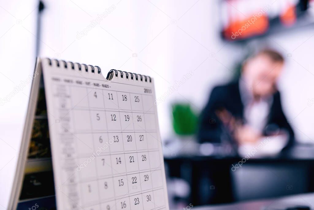 White Office Calendar 2020 on desk with blurred manager working in office on background