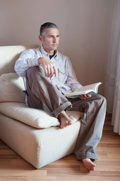Человек на кресле читает книгу — стоковое фото