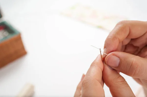 Hands put thread on the needle — Stock Photo, Image