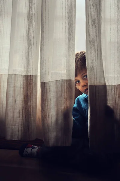 Ребенок, спрятанный за шторами — стоковое фото