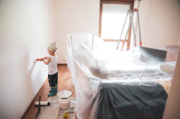 Kind schilder schildert witte muren met borstel en krant papier — Stockfoto