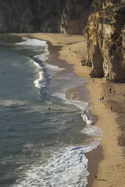Okyanus dalgaları ve kum uçurumlar yanındaki