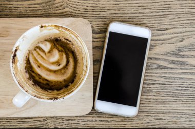 Beyaz smartphone ve kahve fincanı