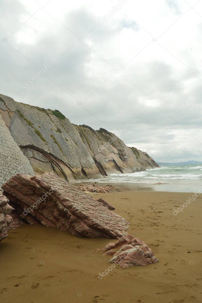 Pieces Of Pink Sandstone Wall Composed Of Fossil Records With Formations Of The Flysch Type Of The Paleocene Geopark UNESCO Basque Route. Shooting Game Of Thrones. Itzurun Beach. Geology Landscapes Travel. Zumaia Guipouzcoa Basque Country Spain.