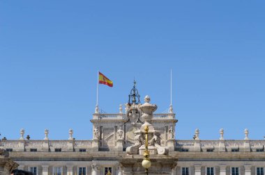 Madrid Kraliyet Sarayı 'nın yüksek cephesi rüzgarda İspanyol bayrağını sallıyor. 15 Haziran 2019. Madrid mi? İspanya. Seyahat Turizm Tatilleri