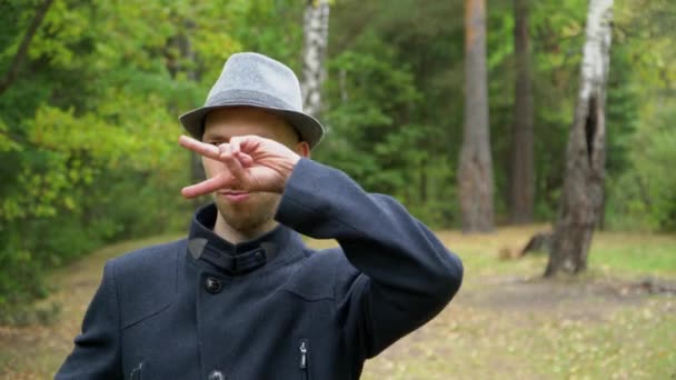 En man i hatt och rock i regnet dansar disco, håller sina händer — Stockvideo