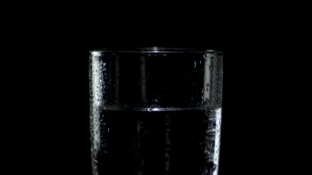 Close-up of a wet glass of water spinning in the dark — Stock Video