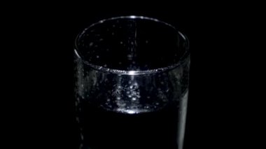 Bardakta su ve damlalar var. Karanlıkta dönüyor.