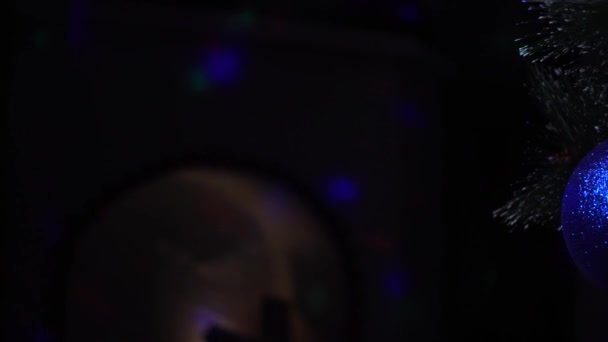 Μπλε χριστουγεννιάτικη μπάλα στο σκοτάδι στο τρεμοπαίξιμο των έγχρωμων φώτων — Αρχείο Βίντεο