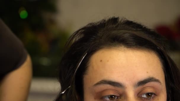Стиліст виконує фіксацію зачіски для брюнетки — стокове відео