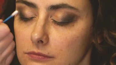 Pamuklu çubukla makyaj sanatçısı kozmetik ürünlerini temizliyor.