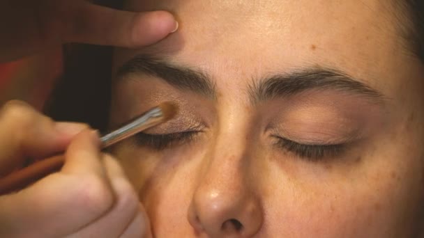发型师用刷子给一个女孩的眼睑蒙上阴影 — 图库视频影像