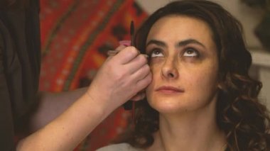 Makyöz, bir kız modelin göz kapaklarını boyar.