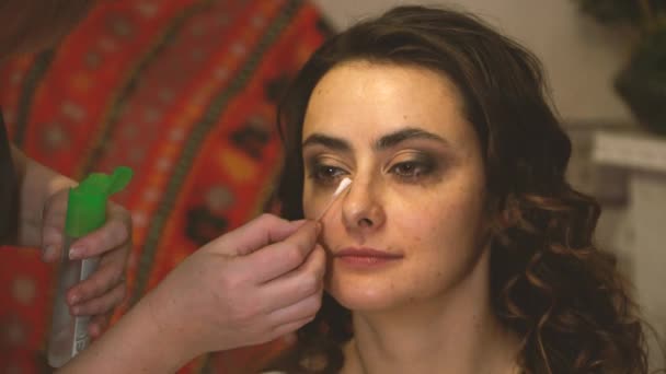 Makeup artist med en bomullstuss bryr sig om en flickor ansikte — Stockvideo