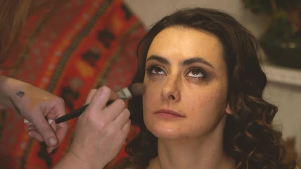 Makeup καλλιτέχνης με ένα πινέλο βάζει μακιγιάζ στο πρόσωπο ενός μοντέλου κορίτσι — Αρχείο Βίντεο