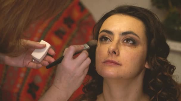 Maquillaje artista con un cepillo aplica base tonal a la cara de las niñas — Vídeos de Stock